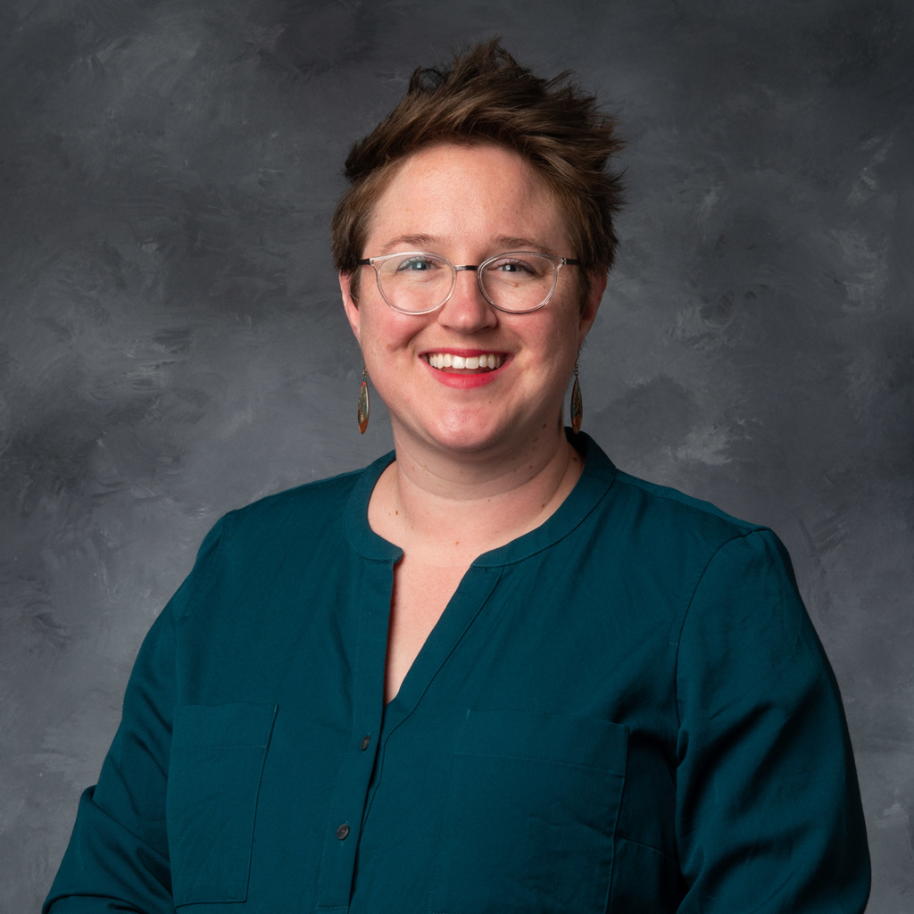 woman with brown hair, glasses, and a blue shirt
