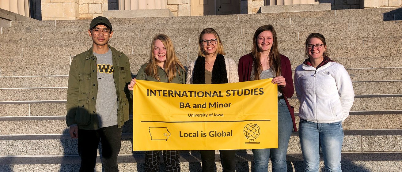 International Studies students holding a banner on the steps of the Old Capitol.